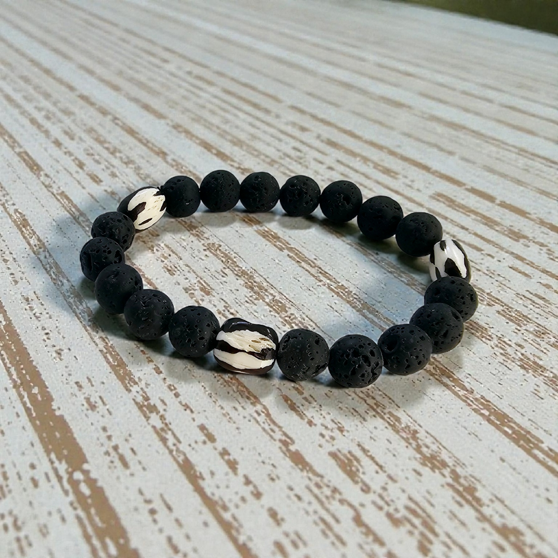 Tibetan Bone Bracelet with 12mm black lava stone beads, designed as a stretch diffuser bracelet for meditation and grounding. This handmade men’s bracelet combines traditional Tibetan jewelry elements with natural lava stones, perfect for essential oils. A meaningful lucky charm and spiritual accessory, ideal for promoting calm and focus. Great handmade gift for him—perfect for yoga, wellness, or daily wear with intention and style.