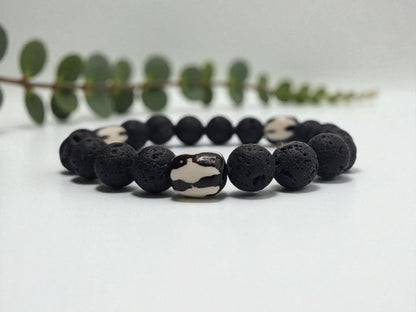 Tibetan Bone Bracelet with 12mm black lava stone beads, designed as a stretch diffuser bracelet for meditation and grounding. This handmade men’s bracelet combines traditional Tibetan jewelry elements with natural lava stones, perfect for essential oils. A meaningful lucky charm and spiritual accessory, ideal for promoting calm and focus. Great handmade gift for him—perfect for yoga, wellness, or daily wear with intention and style.