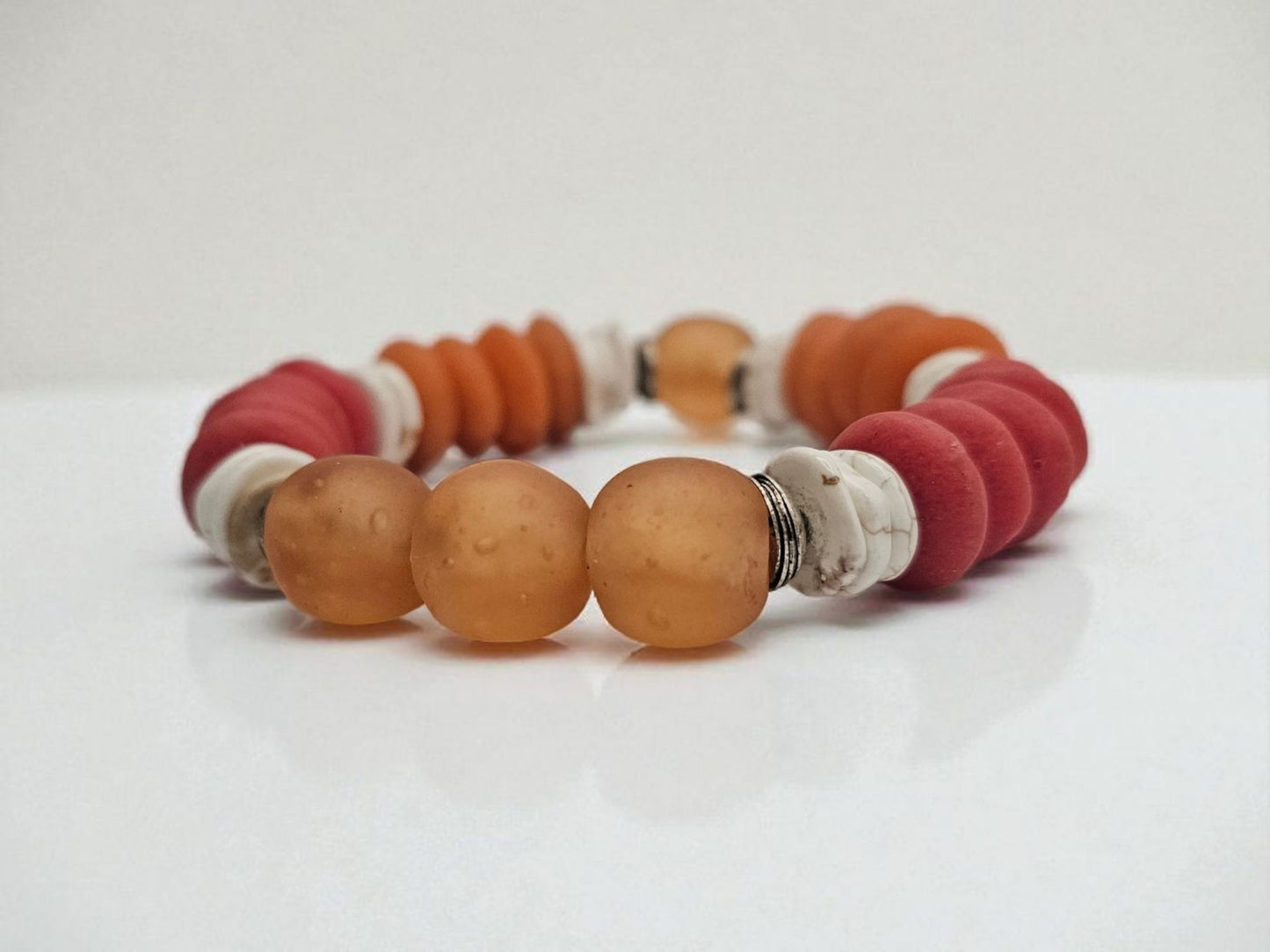 African Ashanti Glass Beaded Bracelet featuring large chunky beads in vibrant orange, red, and white colors, handcrafted into a bold statement jewelry piece for women. This lucky charm Buddha bracelet blends traditional African craftsmanship with modern style, promoting positive energy and spiritual protection. Perfect as a unique gift for her, it combines artisanal quality with eye-catching colors, ideal for everyday wear or special occasions.