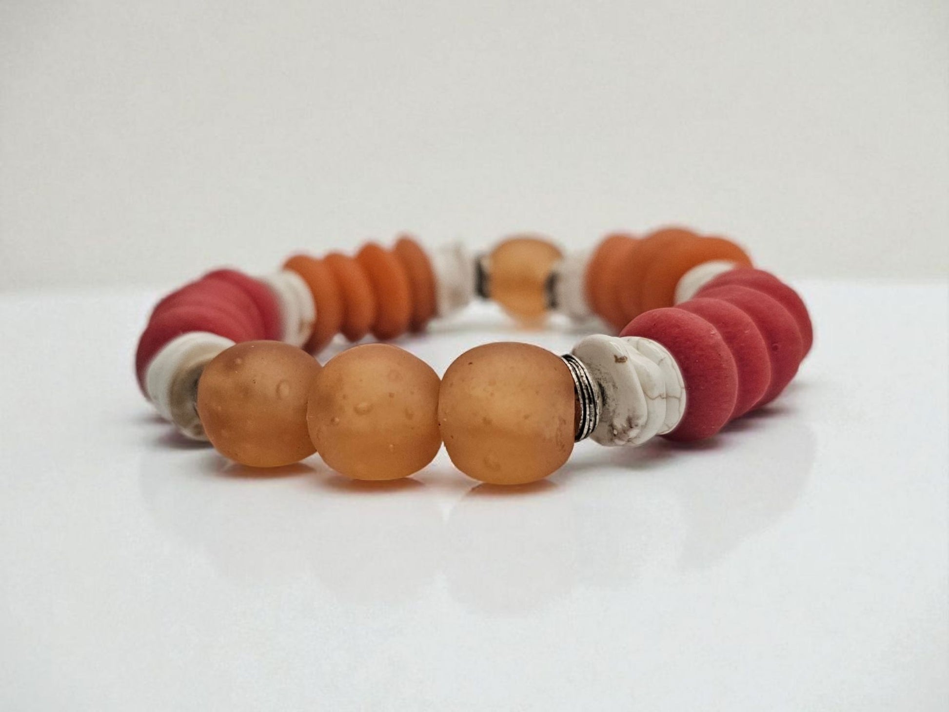 African Ashanti Glass Beaded Bracelet featuring large chunky beads in vibrant orange, red, and white colors, handcrafted into a bold statement jewelry piece for women. This lucky charm Buddha bracelet blends traditional African craftsmanship with modern style, promoting positive energy and spiritual protection. Perfect as a unique gift for her, it combines artisanal quality with eye-catching colors, ideal for everyday wear or special occasions.