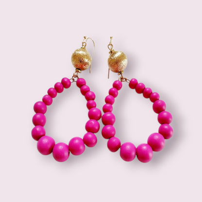 Fuchsia Resin Teardrop Hoop Earrings combined with natural wood beaded round dangles, creating a unique handmade boho statement piece for women. These vibrant, lightweight earrings blend bold resin color with earthy textures, perfect for adding a pop of color and artistic flair to any outfit. Ideal as a thoughtful gift or festival accessory, they showcase expert craftsmanship and a stylish mix of modern and natural elements for free-spirited, fashion-forward individuals.