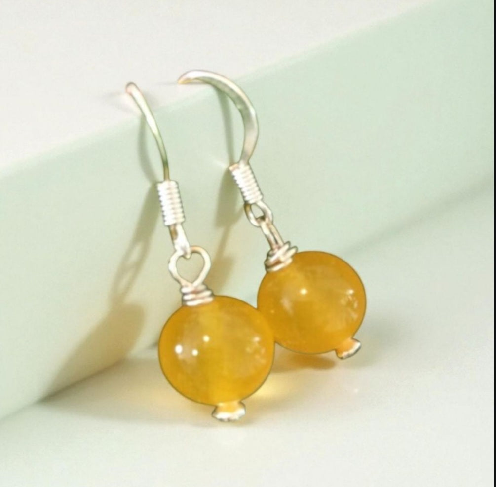Handcrafted Yellow Jade Earrings featuring round gemstone beads paired with elegant topaz drop accents. These handmade jade jewelry pieces showcase a sophisticated design perfect for women who appreciate natural gemstones and timeless elegance. Lightweight and stylish, they make a thoughtful gift for special occasions or everyday wear. Combining artisanal craftsmanship with vibrant yellow jade and sparkling topaz, these earrings add a graceful touch to any outfit.