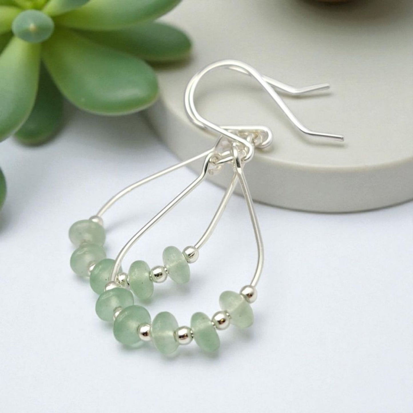 Green Crystal Sterling Silver Earrings featuring handmade dangle design with sea glass hoops, perfect for women who love unique statement jewelry. These artisanal earrings combine vibrant green crystals with delicate sterling silver craftsmanship, creating a stylish and eye-catching accessory. Ideal as a gift for her, they add a touch of natural elegance and boho flair to any outfit. Lightweight and versatile, these earrings are perfect for festivals, casual wear, or special occasions.