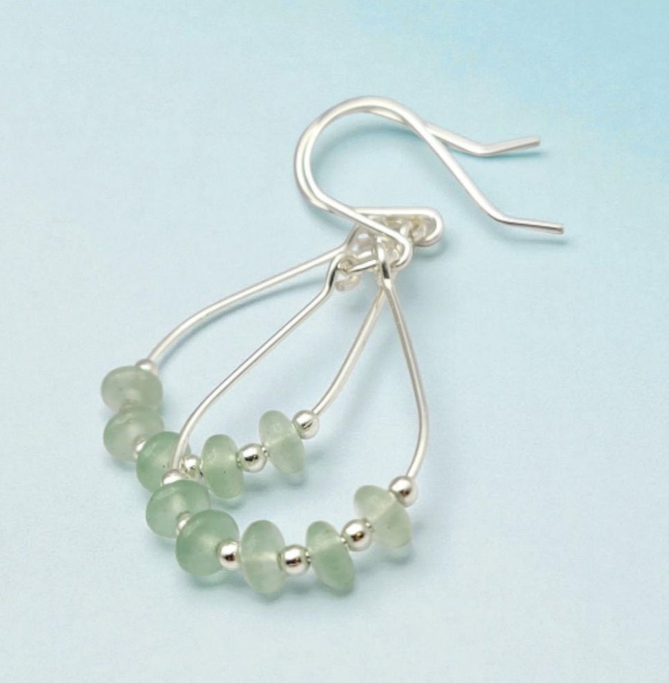 Green Crystal Sterling Silver Earrings featuring handmade dangle design with sea glass hoops, perfect for women who love unique statement jewelry. These artisanal earrings combine vibrant green crystals with delicate sterling silver craftsmanship, creating a stylish and eye-catching accessory. Ideal as a gift for her, they add a touch of natural elegance and boho flair to any outfit. Lightweight and versatile, these earrings are perfect for festivals, casual wear, or special occasions.