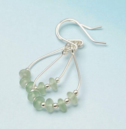 Green Crystal Sterling Silver Earrings featuring handmade dangle design with sea glass hoops, perfect for women who love unique statement jewelry. These artisanal earrings combine vibrant green crystals with delicate sterling silver craftsmanship, creating a stylish and eye-catching accessory. Ideal as a gift for her, they add a touch of natural elegance and boho flair to any outfit. Lightweight and versatile, these earrings are perfect for festivals, casual wear, or special occasions.