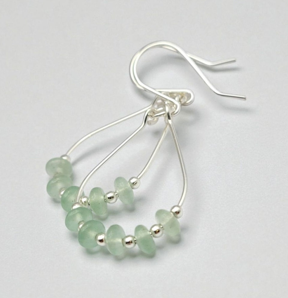 Green Crystal Sterling Silver Earrings featuring handmade dangle design with sea glass hoops, perfect for women who love unique statement jewelry. These artisanal earrings combine vibrant green crystals with delicate sterling silver craftsmanship, creating a stylish and eye-catching accessory. Ideal as a gift for her, they add a touch of natural elegance and boho flair to any outfit. Lightweight and versatile, these earrings are perfect for festivals, casual wear, or special occasions.