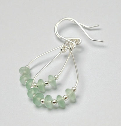 Green Crystal Sterling Silver Earrings featuring handmade dangle design with sea glass hoops, perfect for women who love unique statement jewelry. These artisanal earrings combine vibrant green crystals with delicate sterling silver craftsmanship, creating a stylish and eye-catching accessory. Ideal as a gift for her, they add a touch of natural elegance and boho flair to any outfit. Lightweight and versatile, these earrings are perfect for festivals, casual wear, or special occasions.