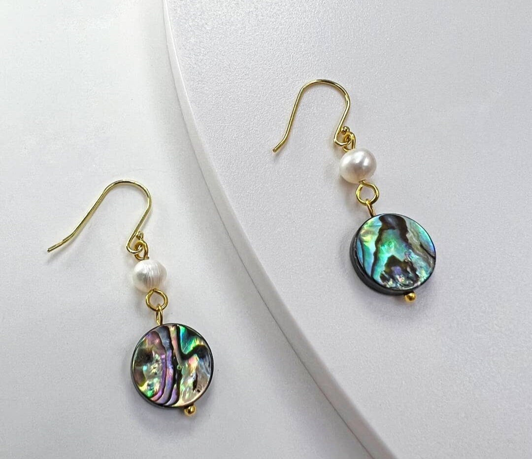 Handmade Abalone Shell Drop Earrings featuring iridescent coin shell pearls in a lightweight dangle design. These dainty and unique earrings for women showcase natural abalone hues with shimmering color shifts, making them a stunning accessory for any outfit. A perfect gift for her, these artisanal earrings blend elegance and simplicity, ideal for birthdays, anniversaries, or special occasions. Stylish, feminine, and one of a kind.