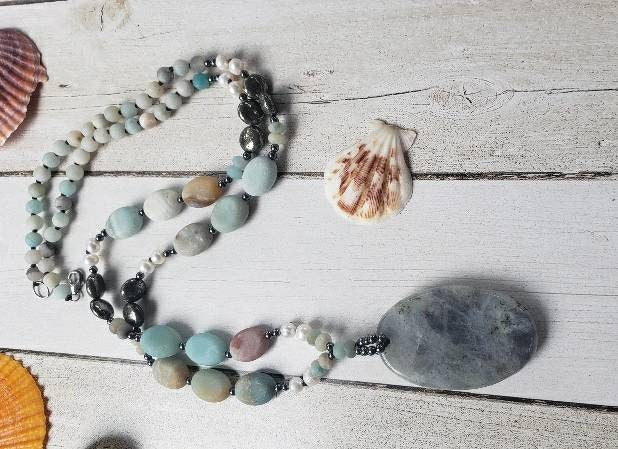 Amazonite and labradorite crystal necklace for women featuring a natural gemstone pendant with soothing tones and subtle shimmer. This handmade statement necklace blends calming amazonite with the iridescent glow of labradorite, offering both beauty and spiritual meaning. Perfect for boho or everyday wear, it makes a thoughtful gift for her. Crafted with care, this unique piece adds a touch of elegance and grounding energy to any jewelry collection