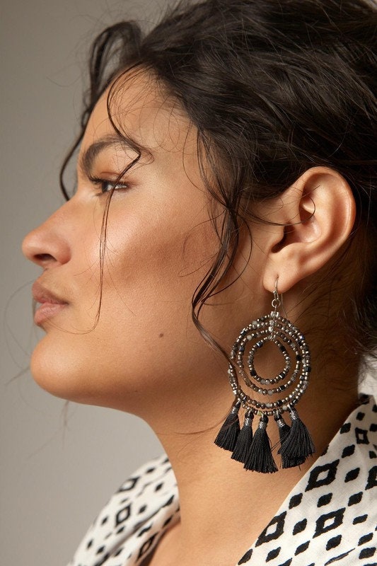 Black Beaded Hoop Earrings with Tassel featuring a bold boho design perfect for women who love trendy, handmade statement jewelry. These eye-catching earrings showcase intricate black beadwork and flowing tassels that add movement and texture to any outfit. Lightweight and stylish, they make a thoughtful gift for her, ideal for birthdays, festivals, or everyday wear. Crafted with care, these earrings offer a chic, free-spirited look that blends modern fashion with artisanal flair.