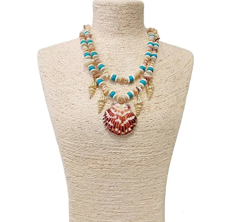 Layered seashell charm pendant necklace featuring blue, beige, and gold tones for a beachy boho look. This coastal jewelry piece captures ocean-inspired elegance with delicate shell charms and soft summer hues. Perfect for beach lovers and bohemian styles, it’s a thoughtful ocean-themed gift for her. Add a touch of seaside charm to your summer style with this lightweight, layered necklace that evokes the beauty of the coast