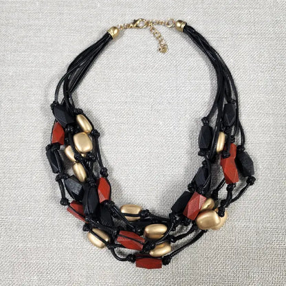 Red gold multi-strand necklace on black cord, featuring a bold boho statement design perfect for layered festival style. This handmade jewelry piece combines vibrant red gold tones with a sleek black cord, adding eye-catching contrast and texture. Ideal as a gift for her, it complements casual and festival outfits with effortless bohemian charm. A versatile accessory to elevate summer looks and outdoor gatherings