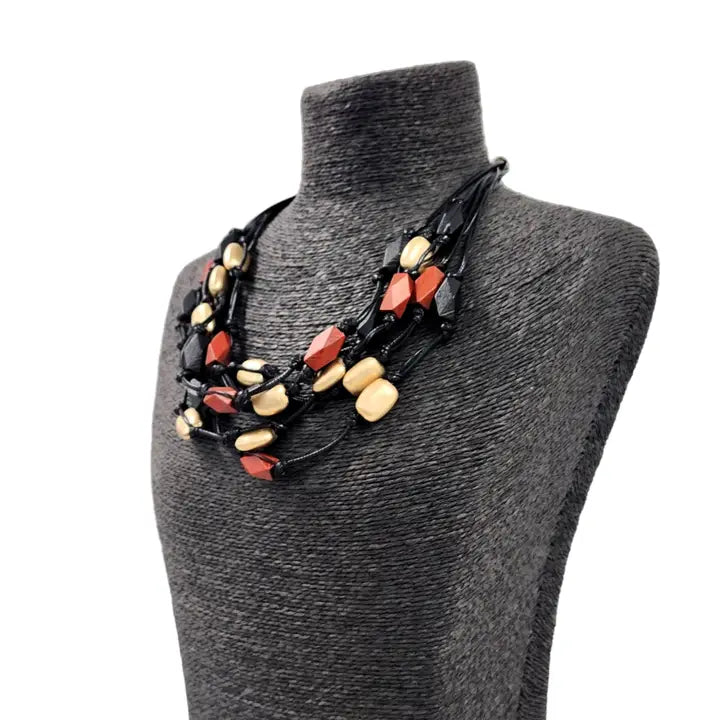 Red gold multi-strand necklace on black cord, featuring a bold boho statement design perfect for layered festival style. This handmade jewelry piece combines vibrant red gold tones with a sleek black cord, adding eye-catching contrast and texture. Ideal as a gift for her, it complements casual and festival outfits with effortless bohemian charm. A versatile accessory to elevate summer looks and outdoor gatherings