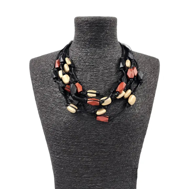Red gold multi-strand necklace on black cord, featuring a bold boho statement design perfect for layered festival style. This handmade jewelry piece combines vibrant red gold tones with a sleek black cord, adding eye-catching contrast and texture. Ideal as a gift for her, it complements casual and festival outfits with effortless bohemian charm. A versatile accessory to elevate summer looks and outdoor gatherings