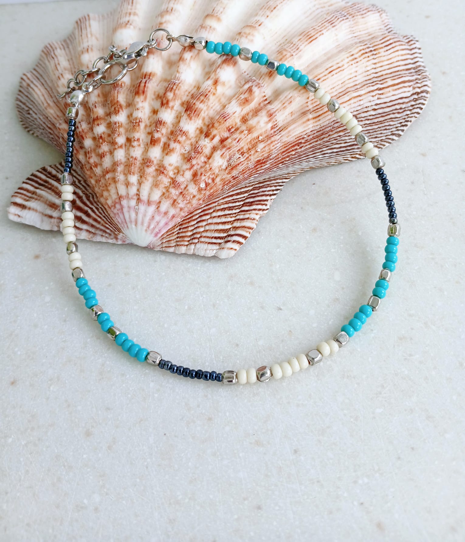 Cream Turquoise Beaded Anklet for Women featuring silver accent beads, handcrafted for a stylish boho beach vibe. This adjustable ankle bracelet blends natural cream and turquoise tones, making it a perfect summer foot accessory. Lightweight and comfortable, it's ideal for beachwear, festivals, or casual outfits. A thoughtful handmade gift for women who love bohemian jewelry and coastal-inspired fashion. Great for layering or wearing solo.