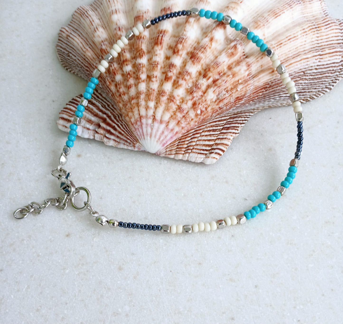 Cream Turquoise Beaded Anklet for Women featuring silver accent beads, handcrafted for a stylish boho beach vibe. This adjustable ankle bracelet blends natural cream and turquoise tones, making it a perfect summer foot accessory. Lightweight and comfortable, it's ideal for beachwear, festivals, or casual outfits. A thoughtful handmade gift for women who love bohemian jewelry and coastal-inspired fashion. Great for layering or wearing solo.