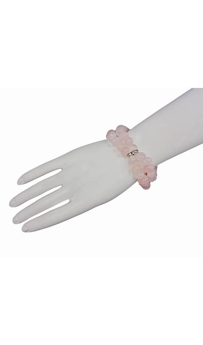 May include: A double-strand bracelet made of light pink rose quartz beads. The beads are smooth and oval-shaped. The bracelet has a silver clasp with small clear stones.