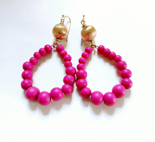 Fuchsia Resin Teardrop Hoop Earrings combined with natural wood beaded round dangles, creating a unique handmade boho statement piece for women. These vibrant, lightweight earrings blend bold resin color with earthy textures, perfect for adding a pop of color and artistic flair to any outfit. Ideal as a thoughtful gift or festival accessory, they showcase expert craftsmanship and a stylish mix of modern and natural elements for free-spirited, fashion-forward individuals.