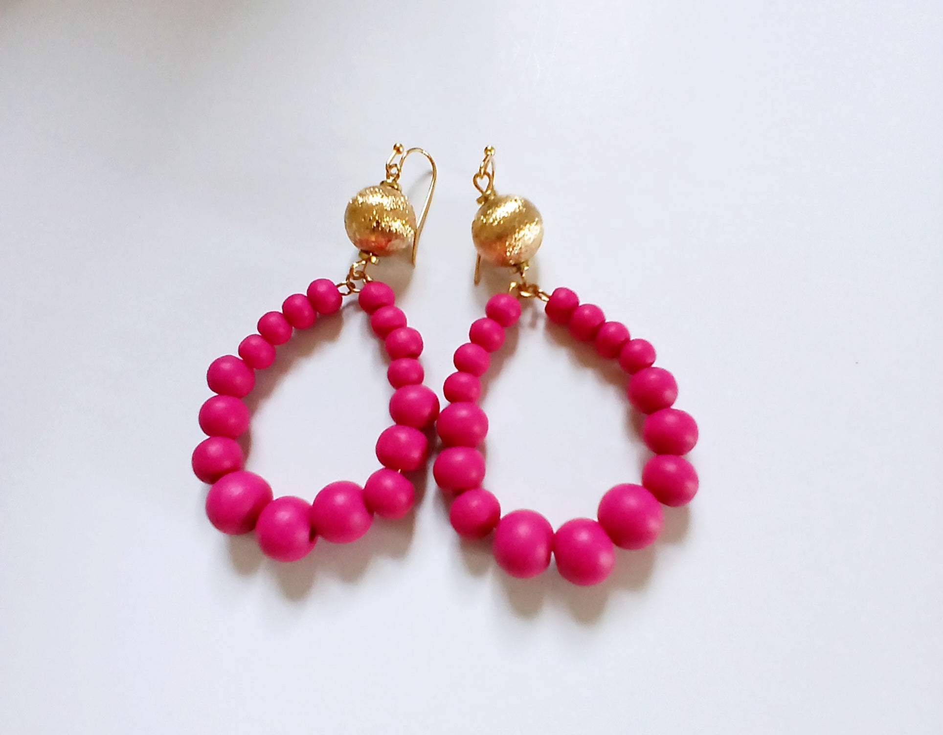 Fuchsia Resin Teardrop Hoop Earrings combined with natural wood beaded round dangles, creating a unique handmade boho statement piece for women. These vibrant, lightweight earrings blend bold resin color with earthy textures, perfect for adding a pop of color and artistic flair to any outfit. Ideal as a thoughtful gift or festival accessory, they showcase expert craftsmanship and a stylish mix of modern and natural elements for free-spirited, fashion-forward individuals.