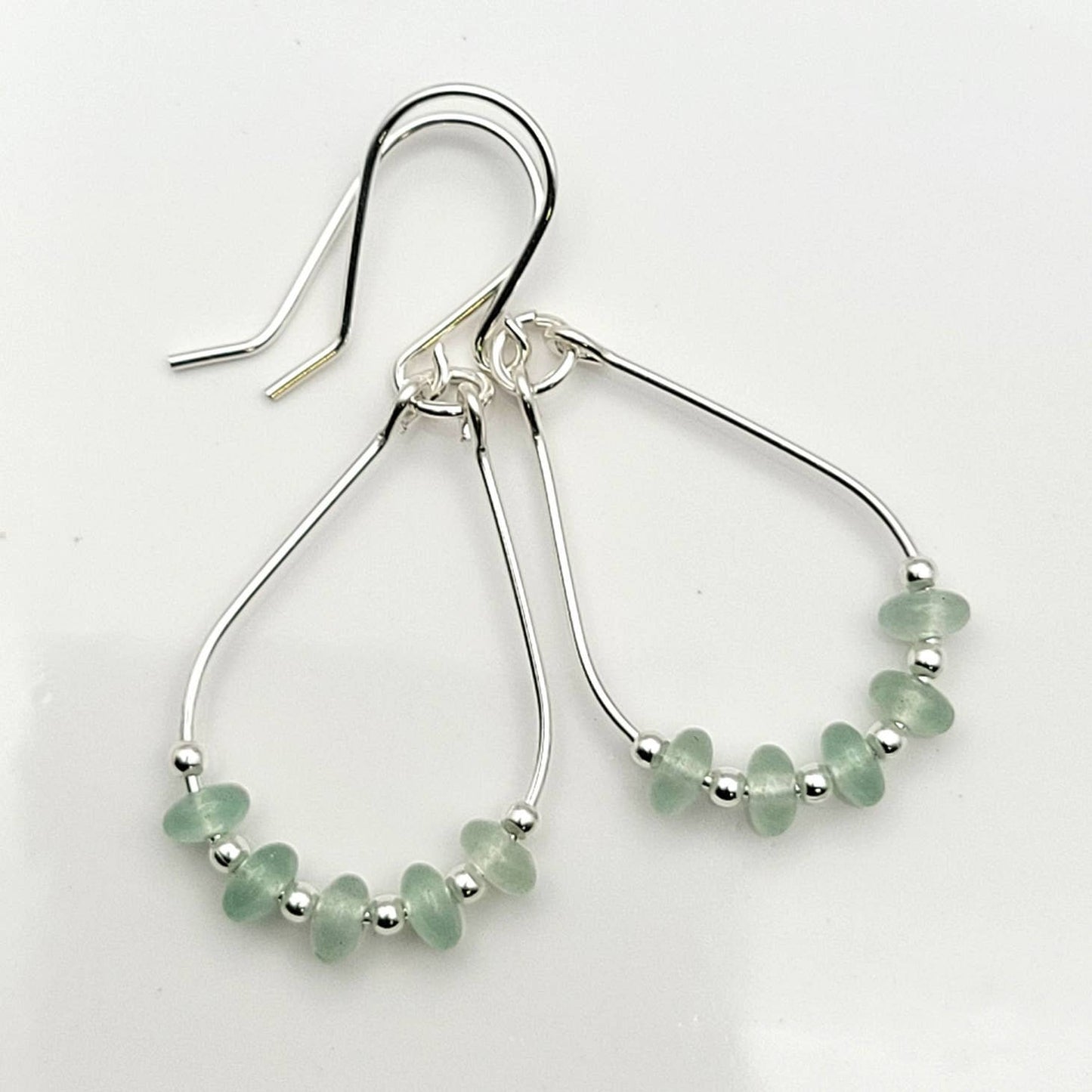 Green Crystal Sterling Silver Earrings featuring handmade dangle design with sea glass hoops, perfect for women who love unique statement jewelry. These artisanal earrings combine vibrant green crystals with delicate sterling silver craftsmanship, creating a stylish and eye-catching accessory. Ideal as a gift for her, they add a touch of natural elegance and boho flair to any outfit. Lightweight and versatile, these earrings are perfect for festivals, casual wear, or special occasions.