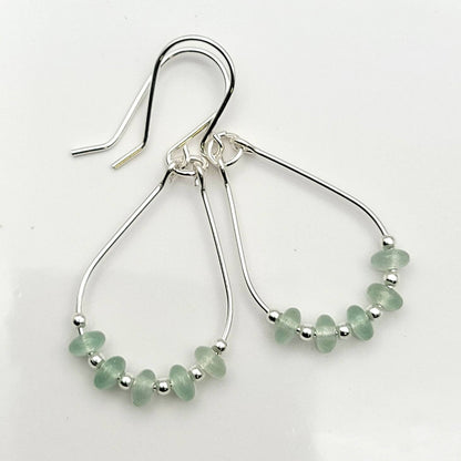Green Crystal Sterling Silver Earrings featuring handmade dangle design with sea glass hoops, perfect for women who love unique statement jewelry. These artisanal earrings combine vibrant green crystals with delicate sterling silver craftsmanship, creating a stylish and eye-catching accessory. Ideal as a gift for her, they add a touch of natural elegance and boho flair to any outfit. Lightweight and versatile, these earrings are perfect for festivals, casual wear, or special occasions.