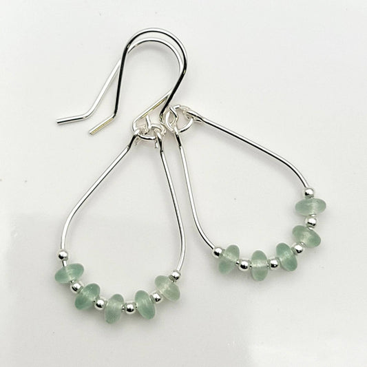 Green Crystal Sterling Silver Earrings featuring handmade dangle design with sea glass hoops, perfect for women who love unique statement jewelry. These artisanal earrings combine vibrant green crystals with delicate sterling silver craftsmanship, creating a stylish and eye-catching accessory. Ideal as a gift for her, they add a touch of natural elegance and boho flair to any outfit. Lightweight and versatile, these earrings are perfect for festivals, casual wear, or special occasions.
