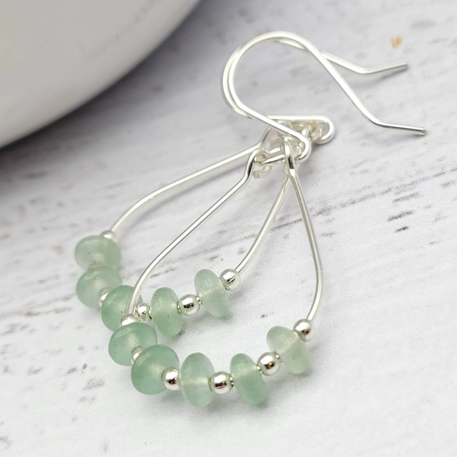 Green Crystal Sterling Silver Earrings featuring handmade dangle design with sea glass hoops, perfect for women who love unique statement jewelry. These artisanal earrings combine vibrant green crystals with delicate sterling silver craftsmanship, creating a stylish and eye-catching accessory. Ideal as a gift for her, they add a touch of natural elegance and boho flair to any outfit. Lightweight and versatile, these earrings are perfect for festivals, casual wear, or special occasions.