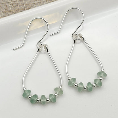 Green Crystal Sterling Silver Earrings featuring handmade dangle design with sea glass hoops, perfect for women who love unique statement jewelry. These artisanal earrings combine vibrant green crystals with delicate sterling silver craftsmanship, creating a stylish and eye-catching accessory. Ideal as a gift for her, they add a touch of natural elegance and boho flair to any outfit. Lightweight and versatile, these earrings are perfect for festivals, casual wear, or special occasions.