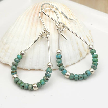 Turquoise & Green Stone Sterling Silver Hoop Earrings featuring long dangle design inspired by Native American jewelry. These handmade earrings combine vibrant turquoise and green gemstones with sterling silver hoops, creating a bold and elegant accessory. Perfect as a bridesmaid gift or a special present for her, they blend cultural artistry with modern boho style. Lightweight and eye-catching, they add a unique, handcrafted touch to any outfit or occasion.