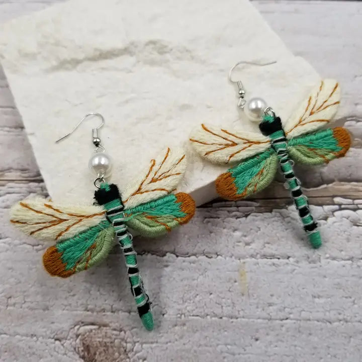 Fall vintage cloth dragonfly earrings featuring intricate fabric wings in earthy autumn tones. These boho statement earrings are perfect for the season, combining rustic charm with nature-inspired elegance. Lightweight and unique, they make a thoughtful fall gift for her. Celebrate autumn with handcrafted dragonfly jewelry that adds a whimsical touch to any outfit. Ideal for bohemian styles and nature lovers alike