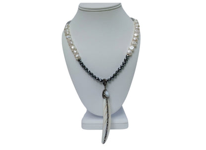 Hematite Mother of Pearl Necklace featuring a minimalist feather shell pendant, handcrafted into an elegant statement piece. This boho chic necklace combines the sleek, reflective hematite beads with the iridescent mother of pearl, creating a unique blend of natural beauty and modern style. Perfect as a gift for women who appreciate artisanal jewelry, it adds subtle sophistication and earthy charm to any outfit, ideal for both casual and formal occasions.