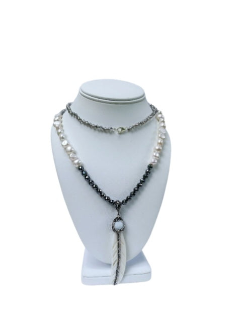 Hematite Mother of Pearl Necklace featuring a minimalist feather shell pendant, handcrafted into an elegant statement piece. This boho chic necklace combines the sleek, reflective hematite beads with the iridescent mother of pearl, creating a unique blend of natural beauty and modern style. Perfect as a gift for women who appreciate artisanal jewelry, it adds subtle sophistication and earthy charm to any outfit, ideal for both casual and formal occasions.