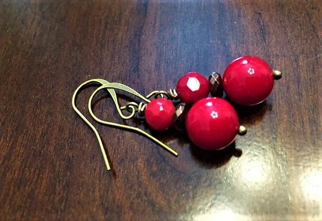 Vintage Tibetan-style hoop earrings crafted with red coral, bronze accents, and red beaded agate stones combined with glass drops. These statement earrings for women feature intricate handcrafted design, blending bold colors and textures for a unique, eye-catching accessory. Perfect for adding a pop of vibrant color to any outfit, these earrings embody ethnic charm and timeless elegance, ideal for special occasions or everyday wear.