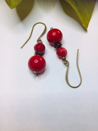 Vintage Tibetan-style hoop earrings crafted with red coral, bronze accents, and red beaded agate stones combined with glass drops. These statement earrings for women feature intricate handcrafted design, blending bold colors and textures for a unique, eye-catching accessory. Perfect for adding a pop of vibrant color to any outfit, these earrings embody ethnic charm and timeless elegance, ideal for special occasions or everyday wear.