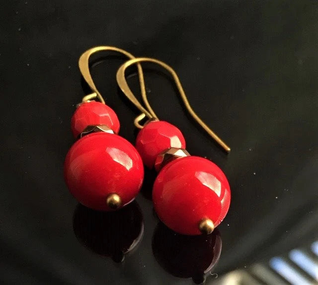 Vintage Tibetan-style hoop earrings crafted with red coral, bronze accents, and red beaded agate stones combined with glass drops. These statement earrings for women feature intricate handcrafted design, blending bold colors and textures for a unique, eye-catching accessory. Perfect for adding a pop of vibrant color to any outfit, these earrings embody ethnic charm and timeless elegance, ideal for special occasions or everyday wear.