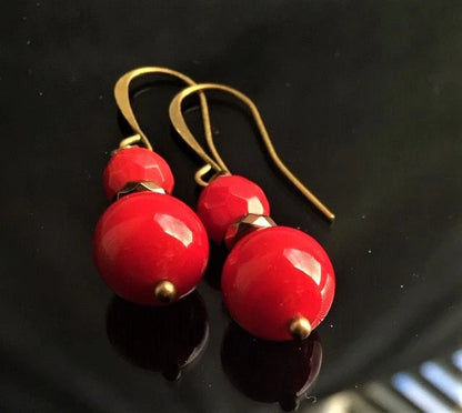 Vintage Tibetan-style hoop earrings crafted with red coral, bronze accents, and red beaded agate stones combined with glass drops. These statement earrings for women feature intricate handcrafted design, blending bold colors and textures for a unique, eye-catching accessory. Perfect for adding a pop of vibrant color to any outfit, these earrings embody ethnic charm and timeless elegance, ideal for special occasions or everyday wear.
