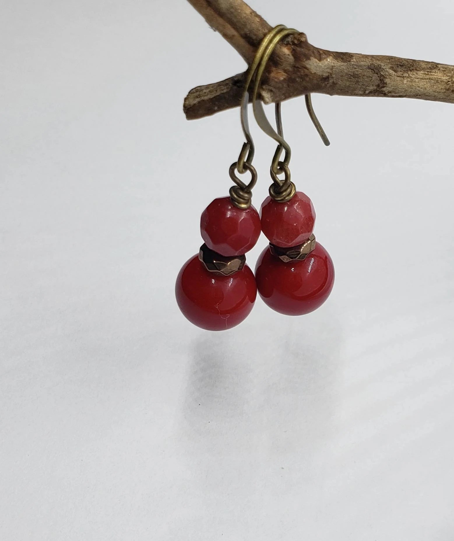 Vintage Tibetan-style hoop earrings crafted with red coral, bronze accents, and red beaded agate stones combined with glass drops. These statement earrings for women feature intricate handcrafted design, blending bold colors and textures for a unique, eye-catching accessory. Perfect for adding a pop of vibrant color to any outfit, these earrings embody ethnic charm and timeless elegance, ideal for special occasions or everyday wear.