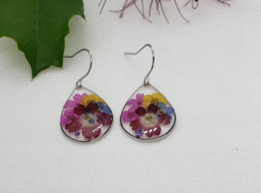 Floral Dried Flower Earrings featuring real dried flowers encased in clear resin teardrop shapes, perfect for summer and boho chic style. These handmade statement earrings capture natural beauty in a lightweight, elegant design ideal for women who love nature-inspired jewelry. A thoughtful gift for birthdays, weddings, or festivals, these unique earrings add a soft, romantic touch to any outfit with their delicate floral charm and artisan craftsmanship.