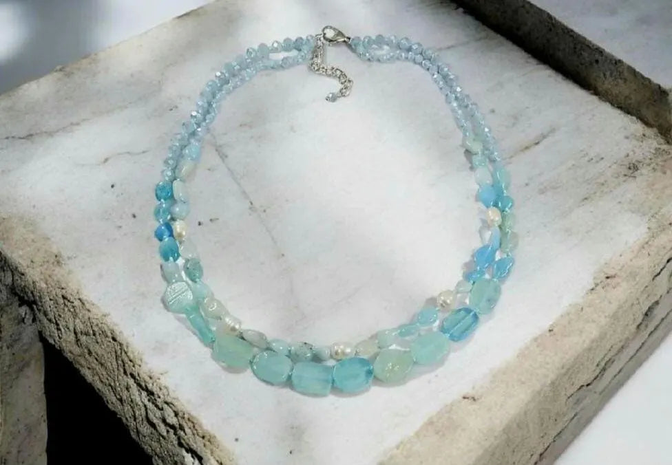 Elegant Aquamarine Necklace featuring natural aquamarine gemstones paired with lustrous freshwater pearls and secured with a sterling silver clasp. This handcrafted jewelry piece combines calming blue tones with classic pearl elegance, creating a versatile accessory for everyday wear or special occasions. Perfect as a thoughtful gift for her, this necklace embodies sophistication, serenity, and artisanal craftsmanship, making it ideal for birthdays, anniversaries, or meaningful celebrations.
