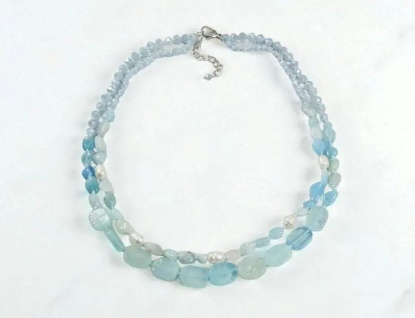 Elegant Aquamarine Necklace featuring natural aquamarine gemstones paired with lustrous freshwater pearls and secured with a sterling silver clasp. This handcrafted jewelry piece combines calming blue tones with classic pearl elegance, creating a versatile accessory for everyday wear or special occasions. Perfect as a thoughtful gift for her, this necklace embodies sophistication, serenity, and artisanal craftsmanship, making it ideal for birthdays, anniversaries, or meaningful celebrations.