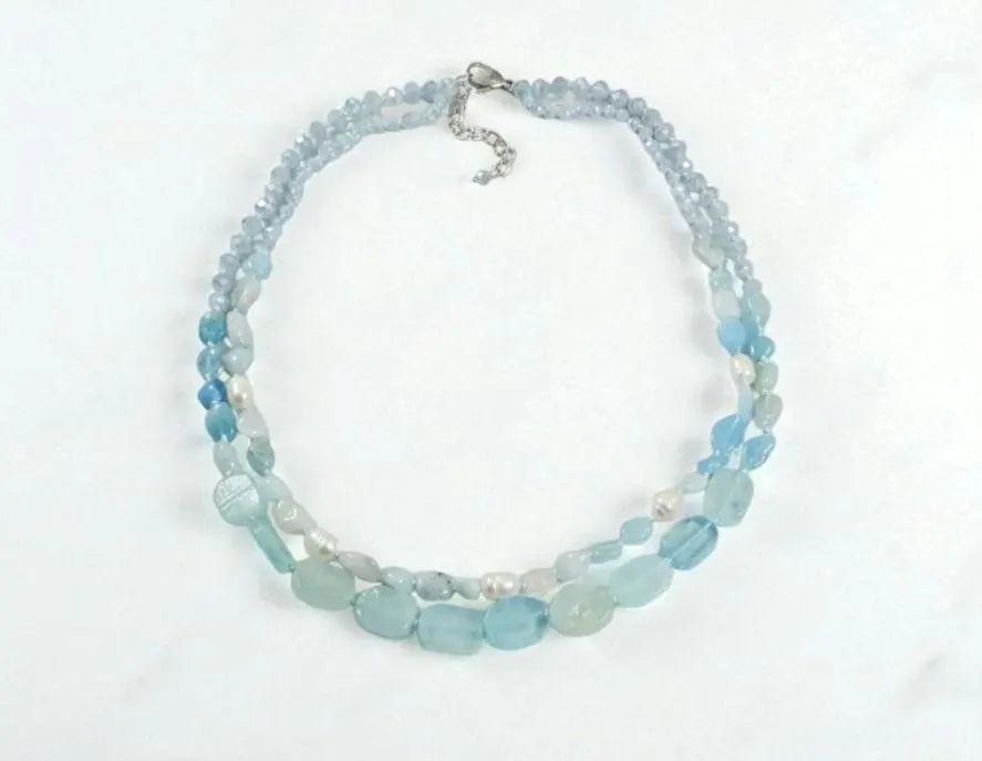 Elegant Aquamarine Necklace featuring natural aquamarine gemstones paired with lustrous freshwater pearls and secured with a sterling silver clasp. This handcrafted jewelry piece combines calming blue tones with classic pearl elegance, creating a versatile accessory for everyday wear or special occasions. Perfect as a thoughtful gift for her, this necklace embodies sophistication, serenity, and artisanal craftsmanship, making it ideal for birthdays, anniversaries, or meaningful celebrations.