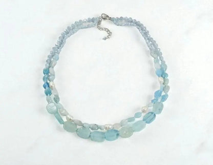 Elegant Aquamarine Necklace featuring natural aquamarine gemstones paired with lustrous freshwater pearls and secured with a sterling silver clasp. This handcrafted jewelry piece combines calming blue tones with classic pearl elegance, creating a versatile accessory for everyday wear or special occasions. Perfect as a thoughtful gift for her, this necklace embodies sophistication, serenity, and artisanal craftsmanship, making it ideal for birthdays, anniversaries, or meaningful celebrations.