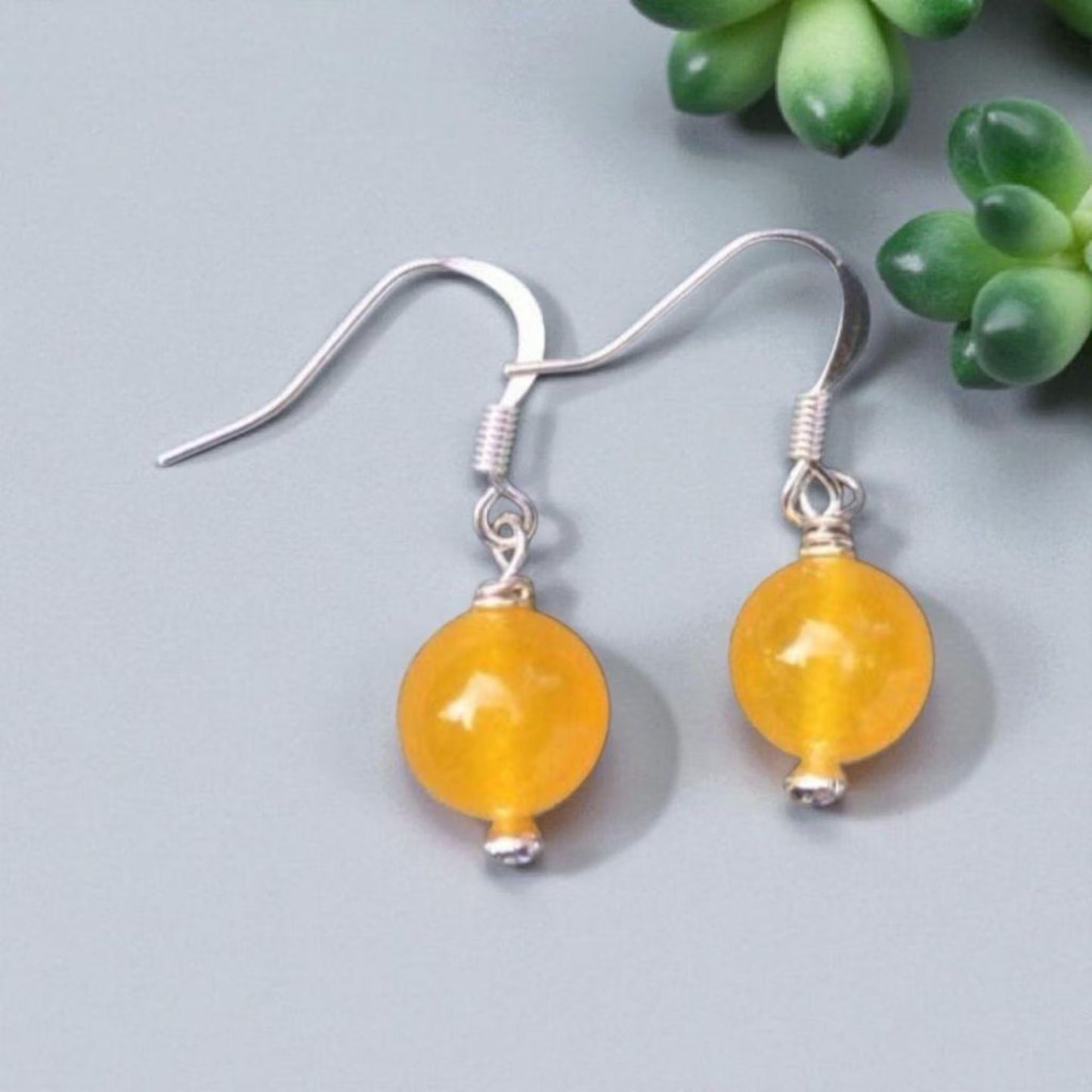 Handcrafted Yellow Jade Earrings featuring round gemstone beads paired with elegant topaz drop accents. These handmade jade jewelry pieces showcase a sophisticated design perfect for women who appreciate natural gemstones and timeless elegance. Lightweight and stylish, they make a thoughtful gift for special occasions or everyday wear. Combining artisanal craftsmanship with vibrant yellow jade and sparkling topaz, these earrings add a graceful touch to any outfit.