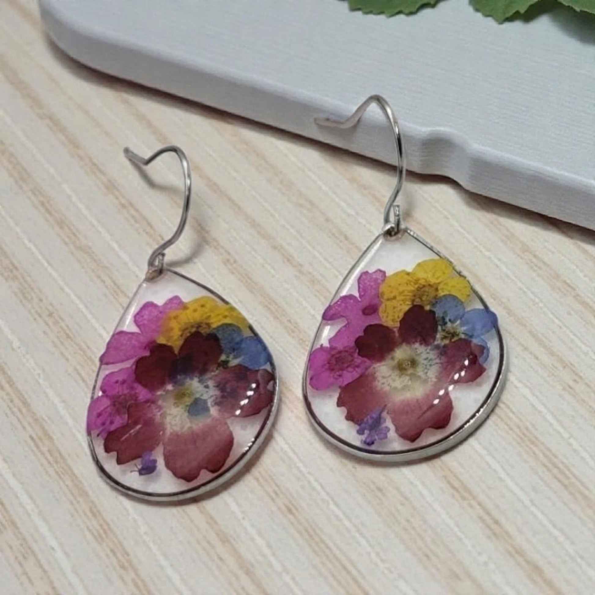 Floral Dried Flower Earrings featuring real dried flowers encased in clear resin teardrop shapes, perfect for summer and boho chic style. These handmade statement earrings capture natural beauty in a lightweight, elegant design ideal for women who love nature-inspired jewelry. A thoughtful gift for birthdays, weddings, or festivals, these unique earrings add a soft, romantic touch to any outfit with their delicate floral charm and artisan craftsmanship.