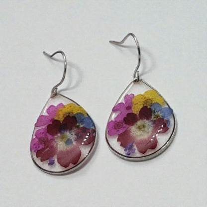 Floral Dried Flower Earrings featuring real dried flowers encased in clear resin teardrop shapes, perfect for summer and boho chic style. These handmade statement earrings capture natural beauty in a lightweight, elegant design ideal for women who love nature-inspired jewelry. A thoughtful gift for birthdays, weddings, or festivals, these unique earrings add a soft, romantic touch to any outfit with their delicate floral charm and artisan craftsmanship.