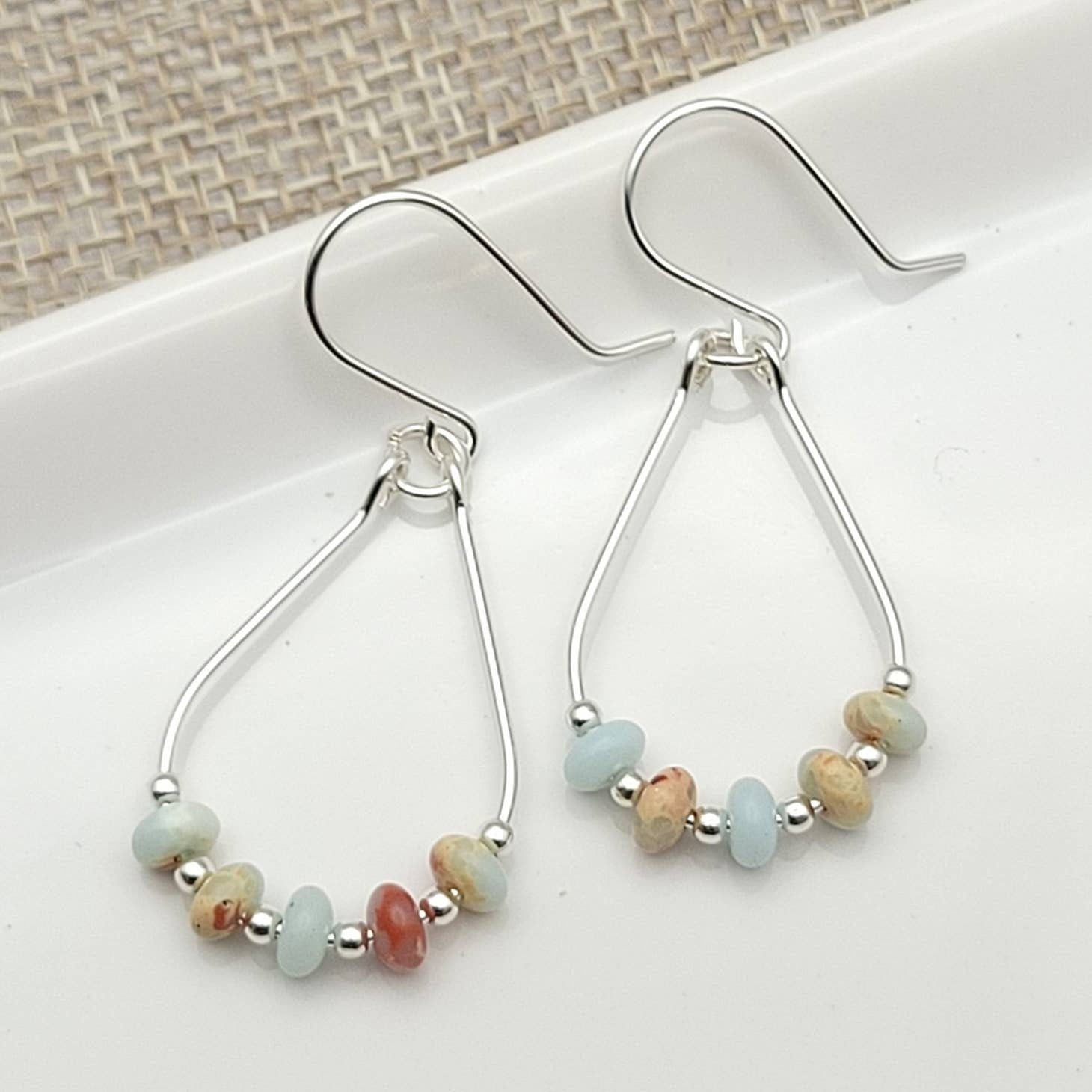Light Blue Jasper Sterling Silver Earrings featuring handmade amazonite teardrop hoops designed for women who love elegant, natural blue jewelry. These artisanal earrings blend soothing jasper and amazonite stones with sterling silver craftsmanship, creating a delicate yet eye-catching accessory. Perfect as a gift for her or a bridesmaid gift, they add a calming, stylish touch to any outfit, ideal for everyday wear or special occasions with a boho-chic flair.