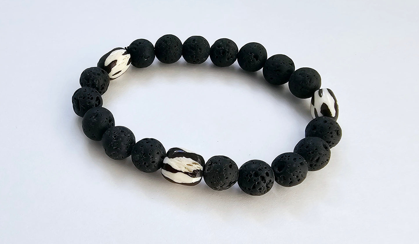 Tibetan Bone Bracelet with 12mm black lava stone beads, designed as a stretch diffuser bracelet for meditation and grounding. This handmade men’s bracelet combines traditional Tibetan jewelry elements with natural lava stones, perfect for essential oils. A meaningful lucky charm and spiritual accessory, ideal for promoting calm and focus. Great handmade gift for him—perfect for yoga, wellness, or daily wear with intention and style.