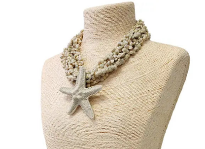 Neutral beige layered seashell and starfish pendant necklace featuring a handmade coastal boho design. This beach jewelry piece showcases natural tones and ocean-inspired elements, perfect for summer outfits. Lightweight and versatile, it adds a subtle yet elegant touch to any look. Ideal as a thoughtful gift for her, this necklace captures the serene beauty of the seaside and complements bohemian style with effortless charm.