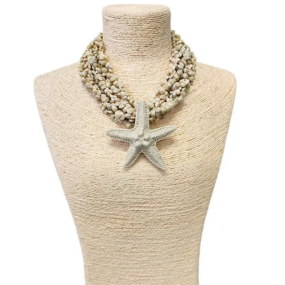 Neutral beige layered seashell and starfish pendant necklace featuring a handmade coastal boho design. This beach jewelry piece showcases natural tones and ocean-inspired elements, perfect for summer outfits. Lightweight and versatile, it adds a subtle yet elegant touch to any look. Ideal as a thoughtful gift for her, this necklace captures the serene beauty of the seaside and complements bohemian style with effortless charm.