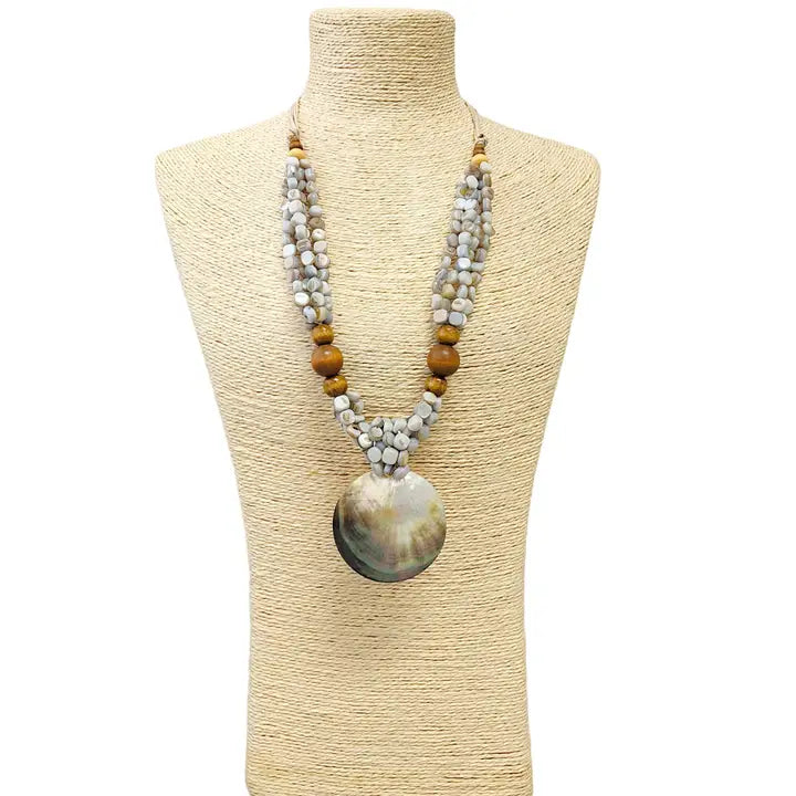 Pastel blue seashell necklace featuring an abalone pendant with natural wood beads, perfect for coastal boho beach style. Inspired by the ocean and mermaid aesthetics, this unique handmade jewelry piece makes a thoughtful gift for sea lovers. Lightweight and easy to wear, it adds a touch of seaside charm to any summer outfit. Ideal for beach vacations, festivals, or casual everyday wear with a nautical, nature-inspired vibe.